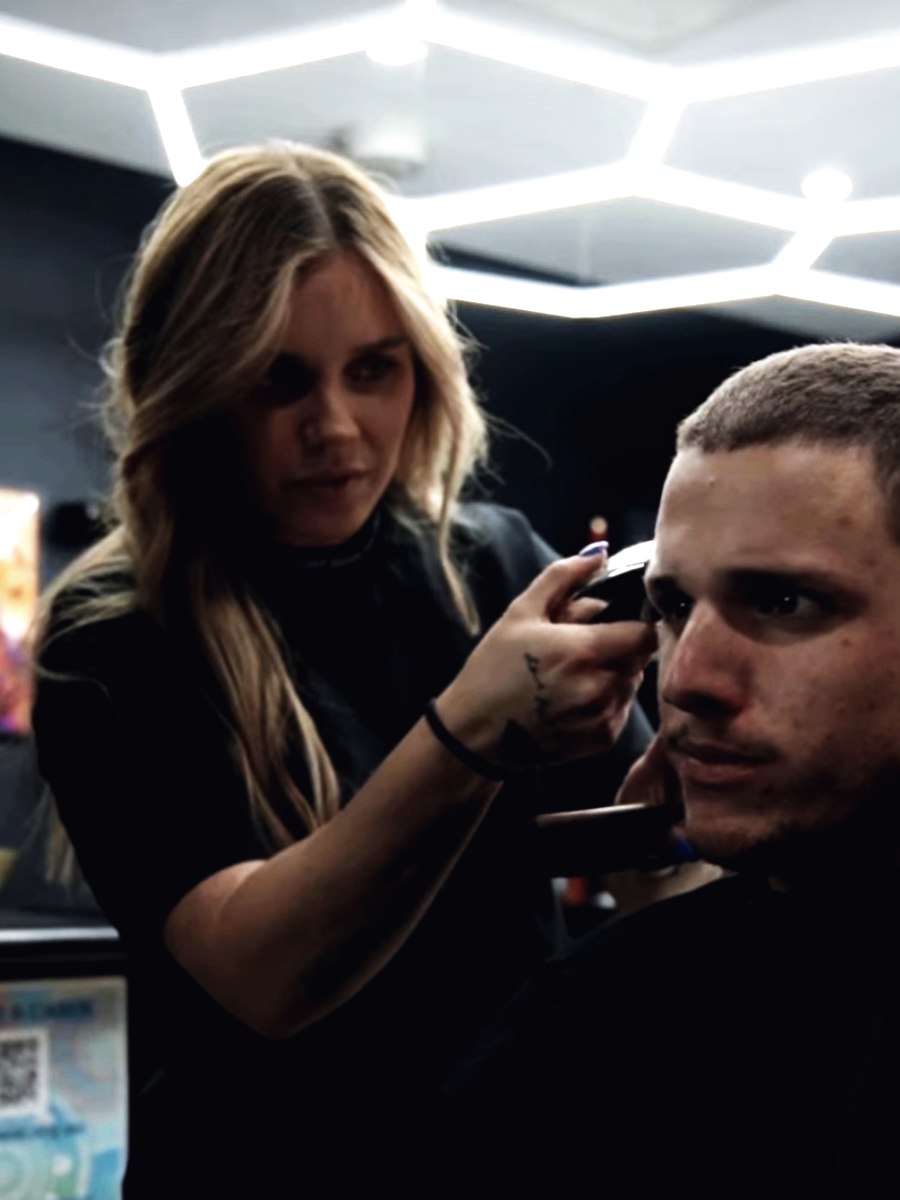 A barber cutting a client under the hexagon lights at Abra & Co